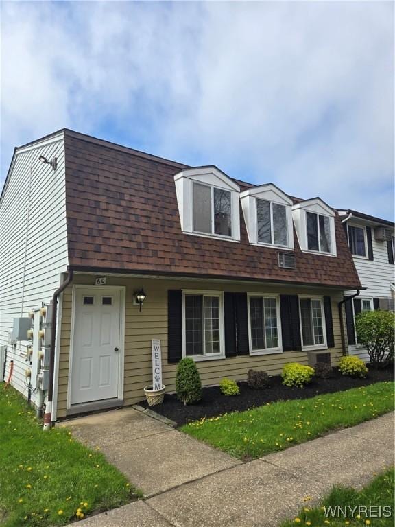view of front facade with a shingled roof, a front yard, and a gambrel roof