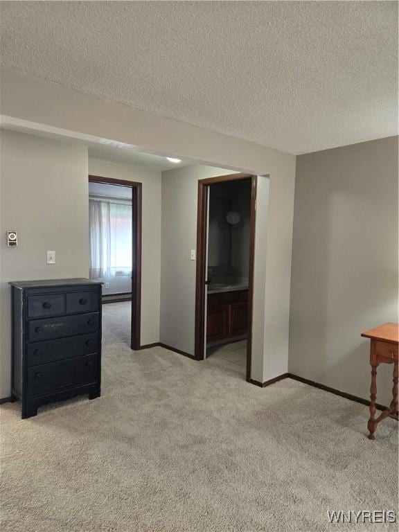 empty room featuring light colored carpet, a textured ceiling, and baseboards