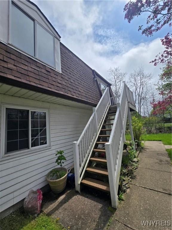 view of exterior entry featuring roof with shingles