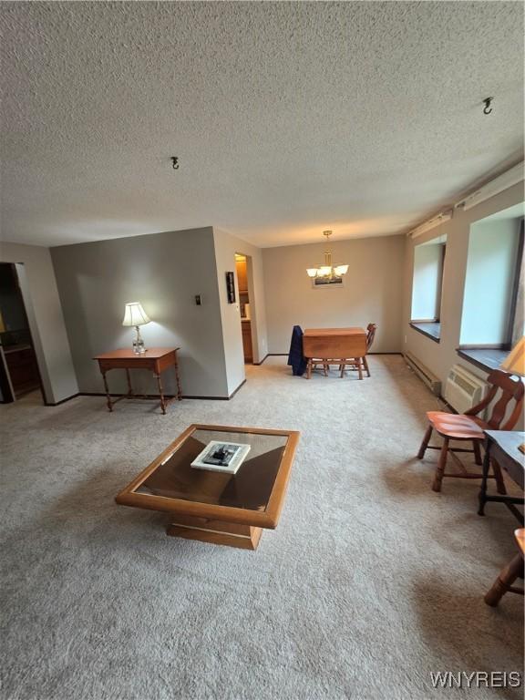 carpeted living room with a chandelier, a textured ceiling, baseboard heating, and baseboards