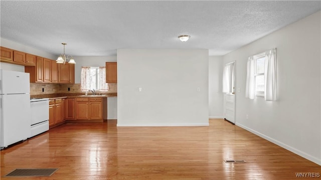 1350 Caravelle Dr, Niagara Falls, NY 14304 - kitchen featuring freestanding refrigerator, range, a sink, light wood finished floors, and a chandelier