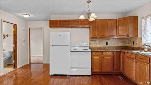 1350 Caravelle Dr, Niagara Falls, NY 14304 - kitchen featuring white appliances, wood finished floors, brown cabinetry, and a textured ceiling