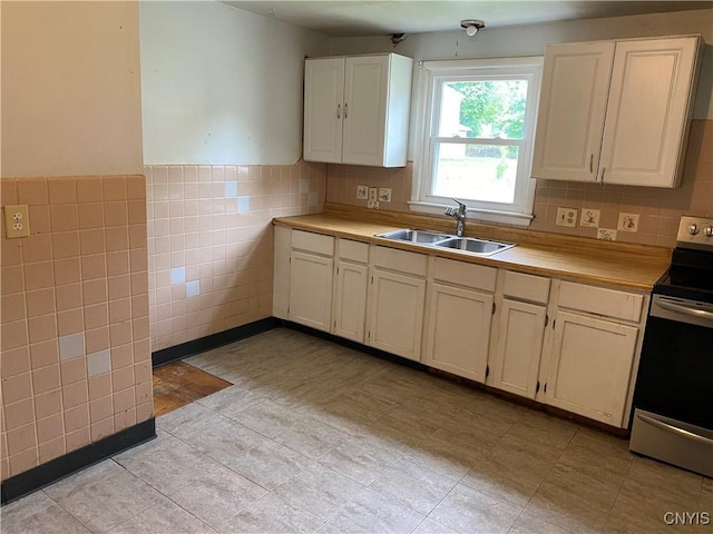 kitchen with electric stove, a sink, light countertops, tile walls, and light tile patterned floors