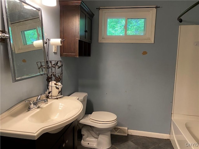bathroom featuring baseboards, healthy amount of natural light, toilet, and vanity