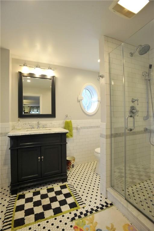 77 Hendy Creek Rd, Big Flats, NY 14905 - full bath with tile walls, a shower stall, wainscoting, vanity, and toilet
