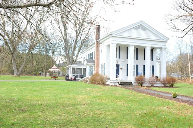 77 Hendy Creek Rd, Big Flats, NY 14905 - neoclassical / greek revival house featuring a chimney, a gazebo, a front yard, covered porch, and a sunroom