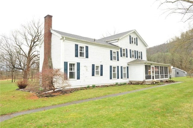 77 Hendy Creek Rd, Big Flats, NY 14905 - view of front of house with a chimney, a sunroom, and a front yard