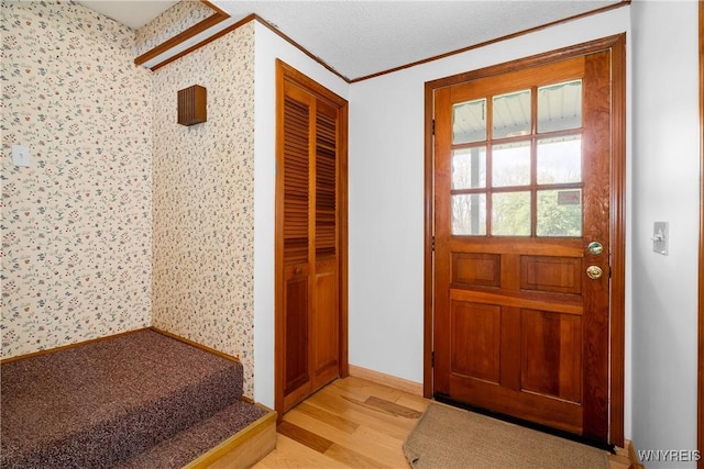 doorway featuring light wood-style floors, ornamental molding, and wallpapered walls