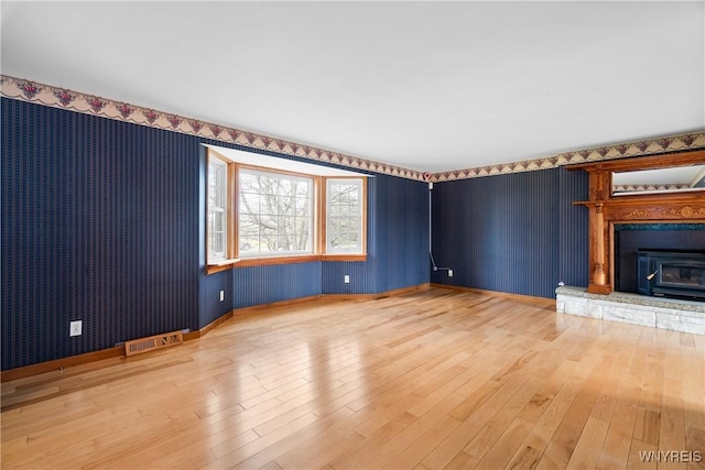 unfurnished living room with a glass covered fireplace and light wood-style flooring