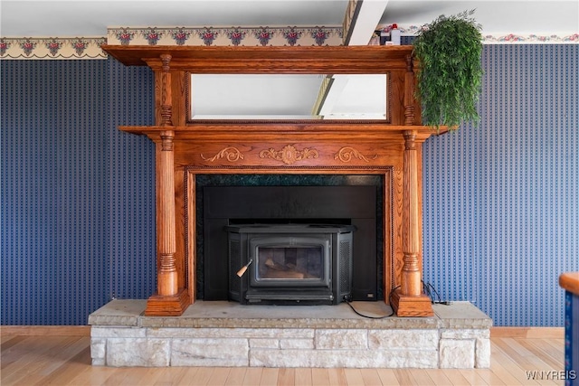 detailed view of wallpapered walls, wood finished floors, baseboards, and a wood stove