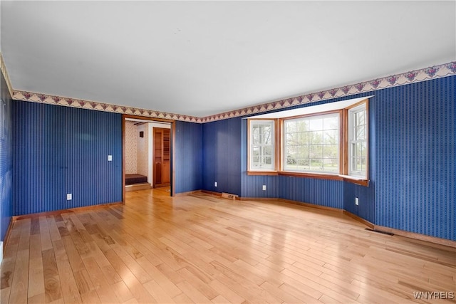 unfurnished room with light wood finished floors, wallpapered walls, and baseboards