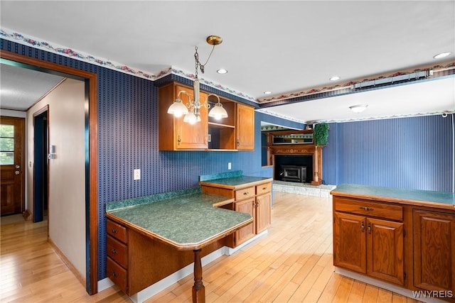kitchen with wallpapered walls, open shelves, light wood finished floors, brown cabinets, and decorative light fixtures