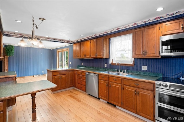 kitchen featuring stainless steel appliances, a sink, brown cabinetry, plenty of natural light, and recessed lighting