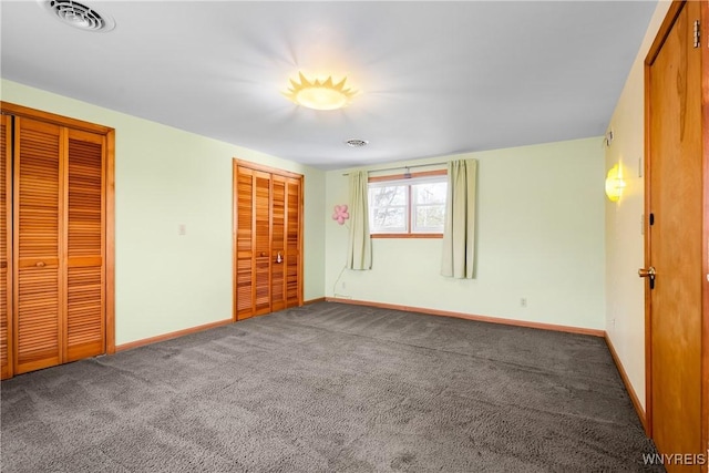 unfurnished bedroom with two closets, carpet floors, and baseboards