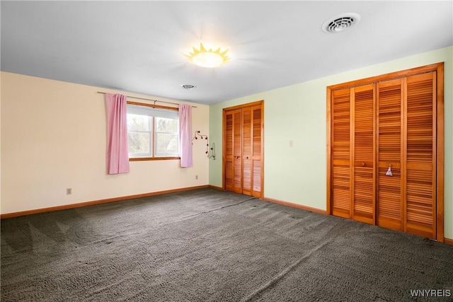 unfurnished bedroom featuring two closets, carpet floors, and baseboards