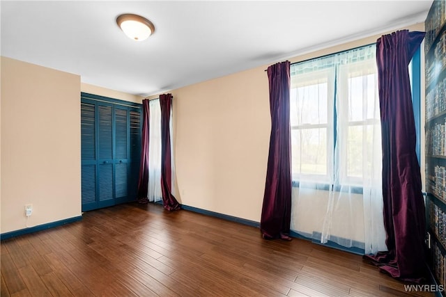 spare room featuring baseboards and wood finished floors