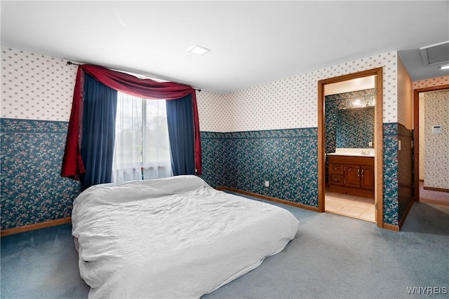 carpeted bedroom featuring wallpapered walls, baseboards, and ensuite bath