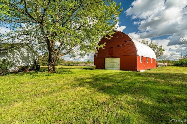 view of green lawn featuring a barn, a garage, and an outbuilding