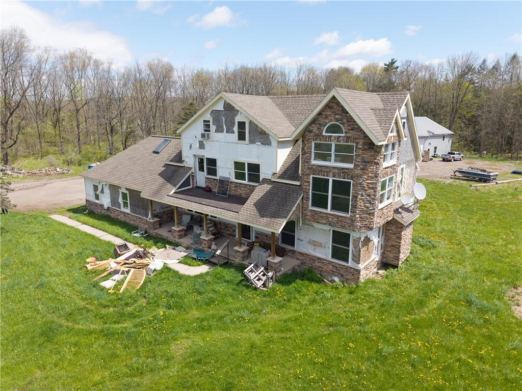 5829 Clark Rd, Conesus, NY 14435 - rear view of house with stone siding, a shingled roof, a yard, a patio area, and stucco siding