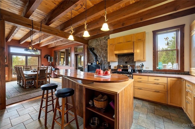 463 Hughes Rd, Russia, NY 13438 - kitchen with a wood stove, wooden ceiling, stainless steel gas stove, stone tile flooring, and a center island