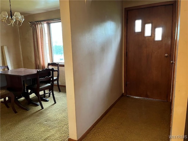 entryway featuring carpet, a chandelier, baseboards, and plenty of natural light