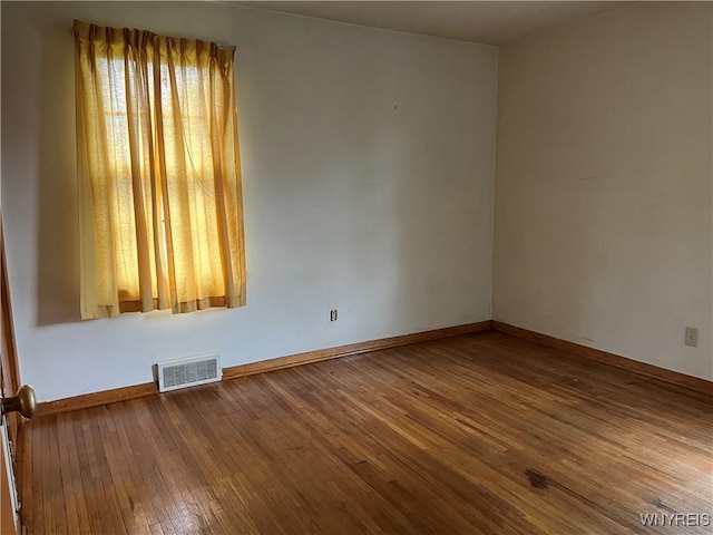 spare room featuring hardwood / wood-style flooring and baseboards