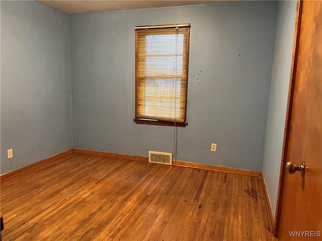 spare room featuring hardwood / wood-style flooring and baseboards