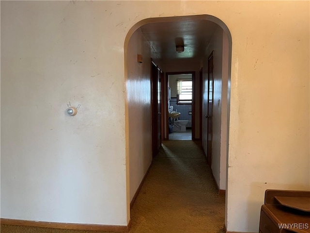 hallway with arched walkways and carpet floors