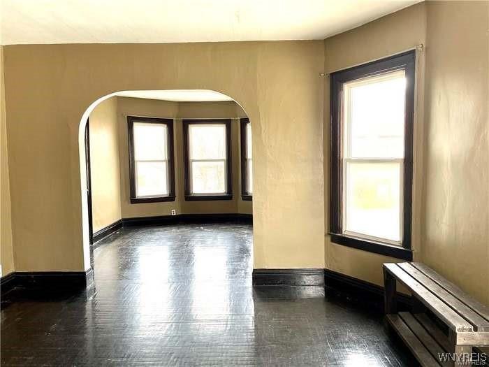 69 Red Jacket Pkwy, Buffalo, NY 14220 - unfurnished room with arched walkways, healthy amount of natural light, and baseboards