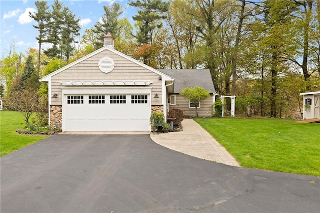 single story home featuring stone siding, driveway, a front lawn, and a chimney