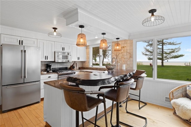 kitchen with stainless steel appliances, dark countertops, a breakfast bar, a peninsula, and crown molding