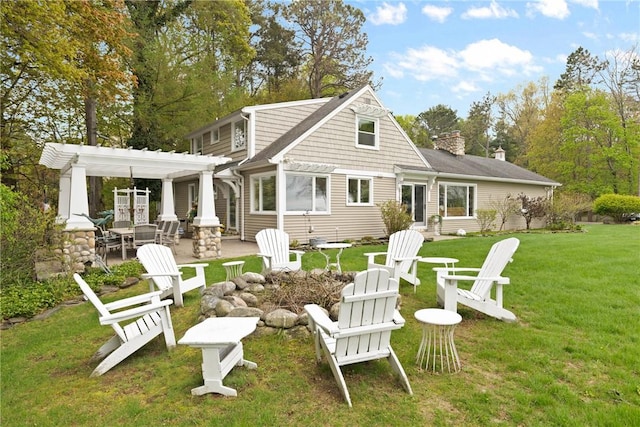 rear view of property with a pergola, an outdoor fire pit, a patio, a yard, and a chimney