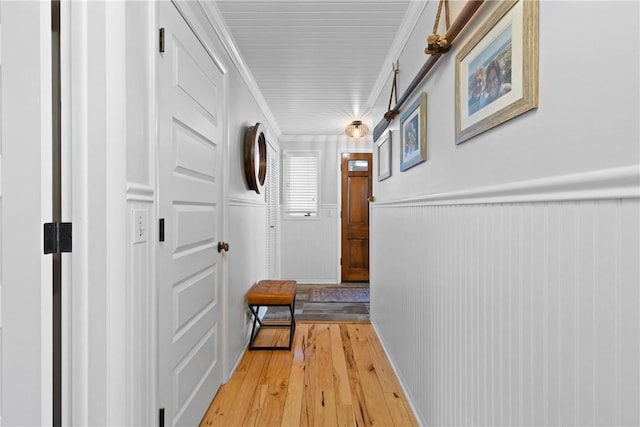 hall with light wood-style floors, a wainscoted wall, and crown molding