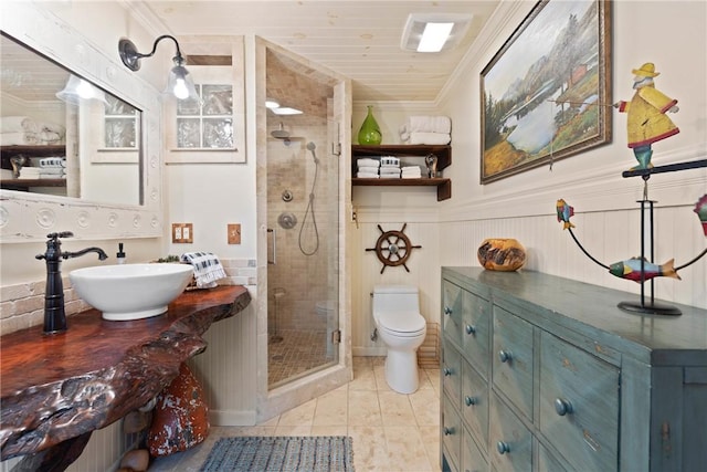 bathroom with a stall shower, toilet, ornamental molding, a wainscoted wall, and vanity