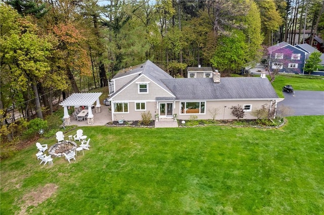 rear view of property featuring a fire pit, a lawn, a pergola, a patio, and a chimney