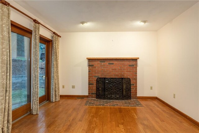48 Hemlock Ln, Erwin, NY 14870 - unfurnished living room featuring a brick fireplace, wood finished floors, and baseboards