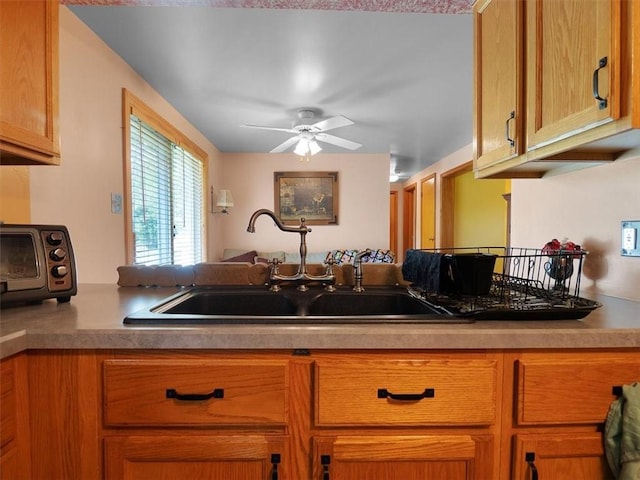 kitchen with a sink, ceiling fan, and brown cabinets
