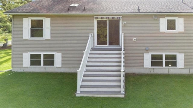back of house with a yard and roof with shingles