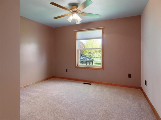 spare room with light colored carpet, a ceiling fan, and baseboards