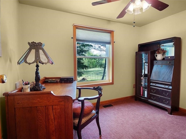 carpeted office space featuring baseboards and a ceiling fan