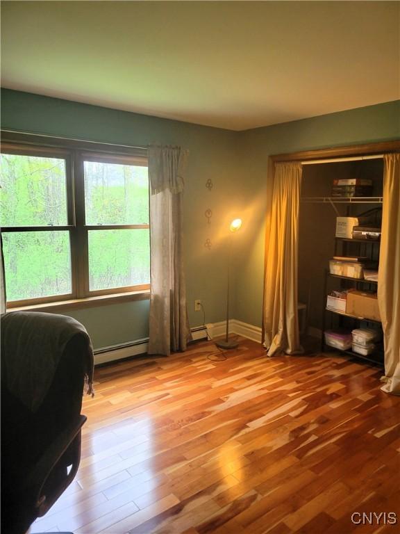 3130 Meadow View Ln, Sennett, NY 13021 - home office featuring a baseboard heating unit, wood finished floors, and baseboards
