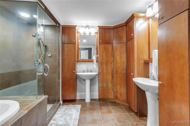 bathroom featuring a stall shower, tile patterned flooring, a bath, and a sink