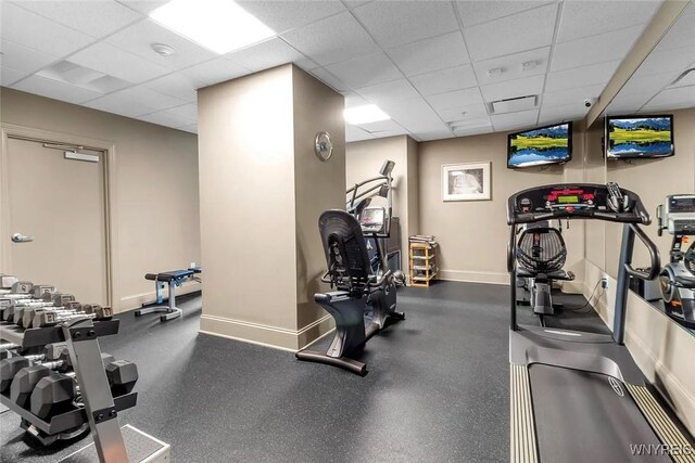 workout area featuring a drop ceiling and baseboards
