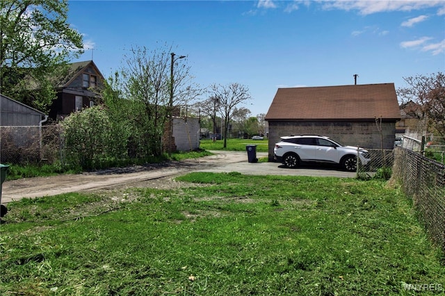 view of yard with fence, a garage, and driveway