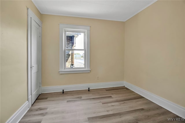unfurnished room featuring ornamental molding, light wood-style flooring, and baseboards