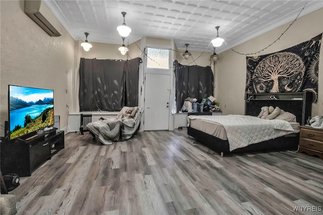 bedroom featuring an AC wall unit, wood finished floors, radiator, and a textured wall