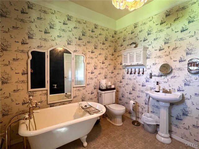1401 Utica St, Whitestown, NY 13424 - full bathroom with a freestanding bath, toilet, vaulted ceiling, wallpapered walls, and baseboards