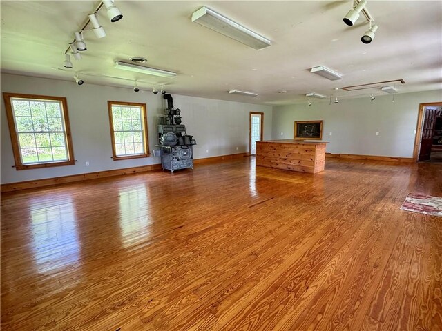225 John Cook Rd, Unadilla, NY 13849 - unfurnished living room featuring rail lighting, a wood stove, wood finished floors, and baseboards