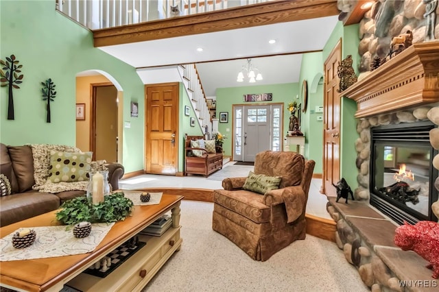 233 Falls Rd, Aurora, NY 14170 - living room with arched walkways, a stone fireplace, recessed lighting, stairway, and a chandelier