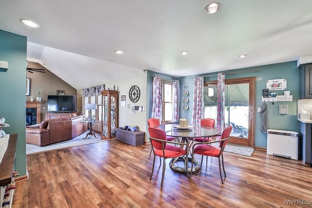 dining room with recessed lighting, wood finished floors, a premium fireplace, and lofted ceiling